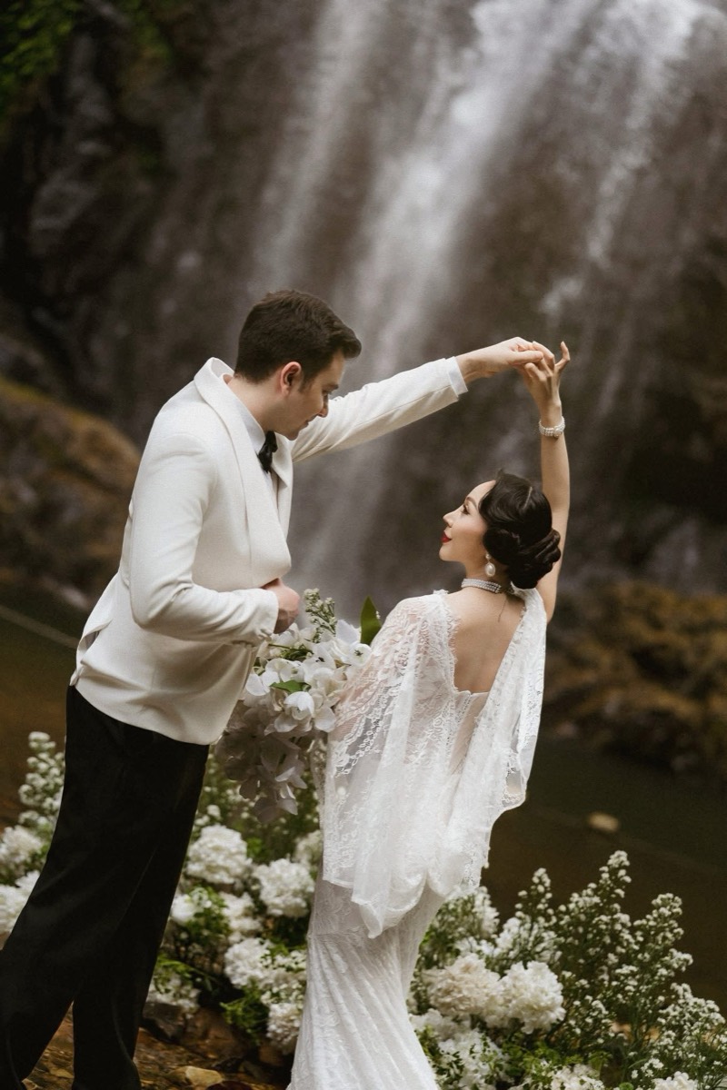 Couple dancing by a waterfall, white florals styled on the rocks by Rootking