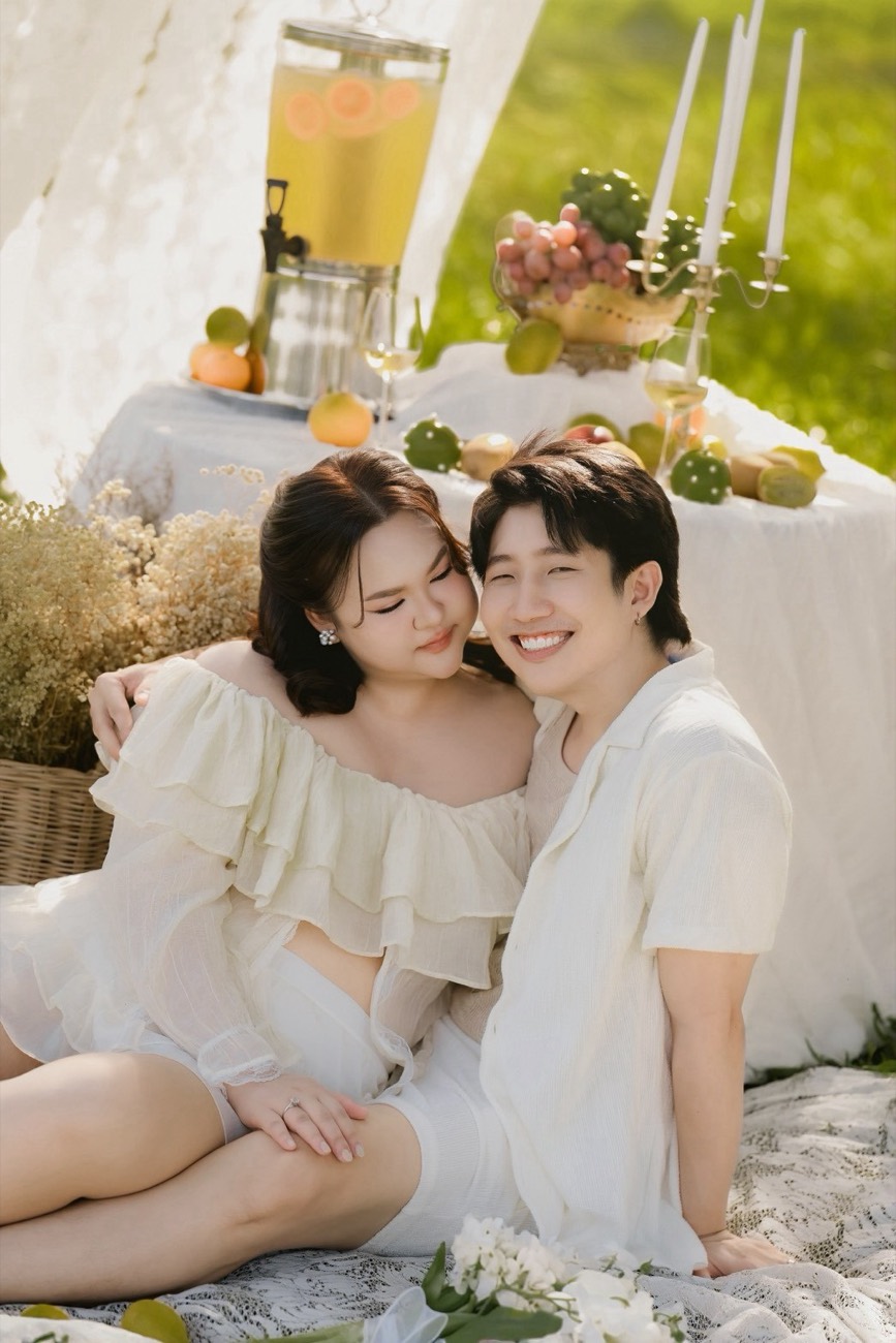 Couple seated together at a garden picnic in soft cream tones